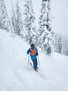 Derek standing on a fairly steep run at Steamboat with snow covered trees in the background